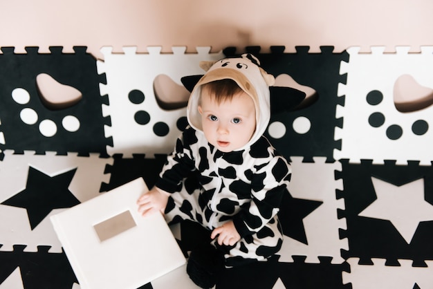 Portrait D Un Charmant Bebe Mignon Un Garcon En Costume Noir Et Blanc Est Assis Et Regarde Un Livre Dans La Maison Photo Premium