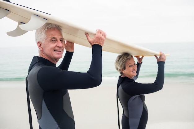 Portrait, de, couples aînés, dans, wetsuit, porter, planche surf, sur, tête Photo Premium
