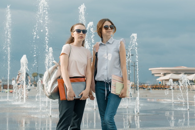 Portrait de deux belles filles avec des sacs à dos près d'une fontaine Photo Premium