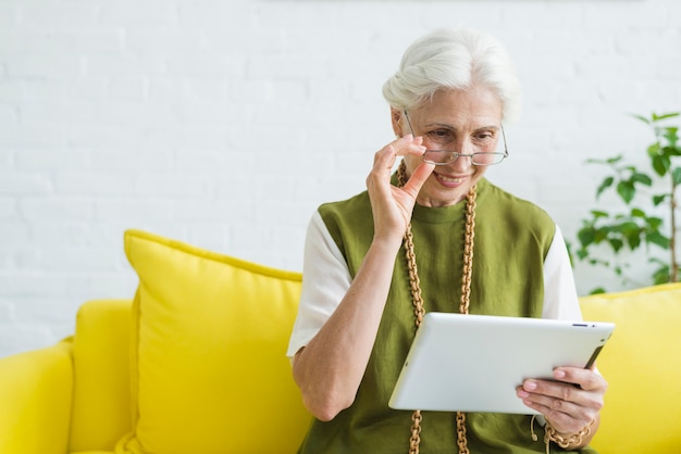 Portrait de femme senior heureuse en regardant tablette numérique Photo gratuit