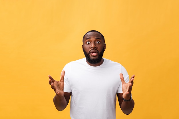 Portrait d'un homme afro-américain avec les mains levées dans le choc et l'incrédulité. isolé sur fond jaune. Photo Premium