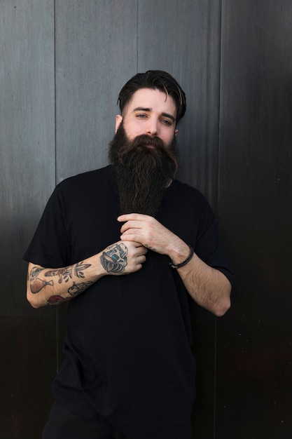 Portrait d'un homme avec un homme long barbu contre un mur en bois noir Photo gratuit