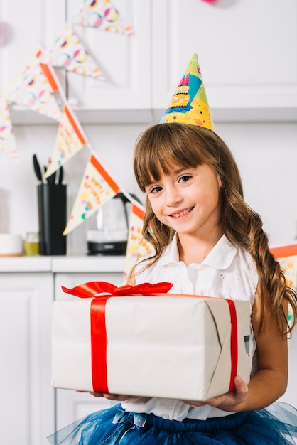 Portrait D Une Jeune Fille Souriante Tenant Une Boite Cadeau Enveloppee Blanche Attachee Avec Un Ruban Rouge Pour Son Anniversaire Photo Gratuite