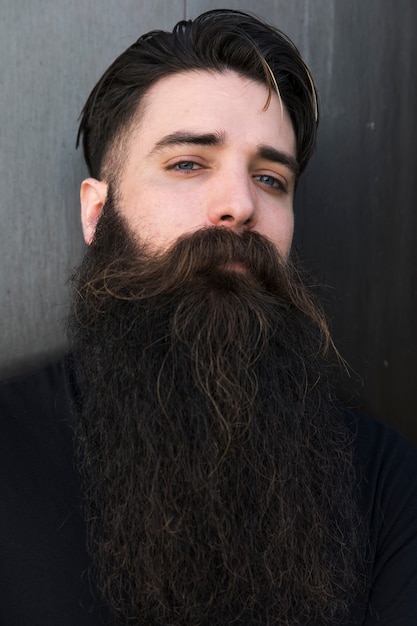 Portrait d'un jeune homme barbu sur fond gris Photo gratuit