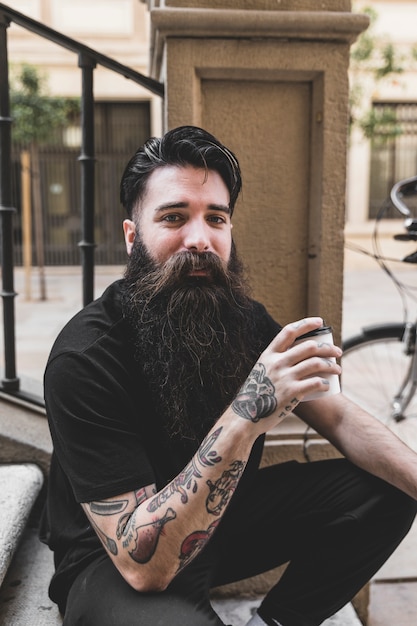 Portrait, jeune, tatouage, main, tasse, café Photo gratuit