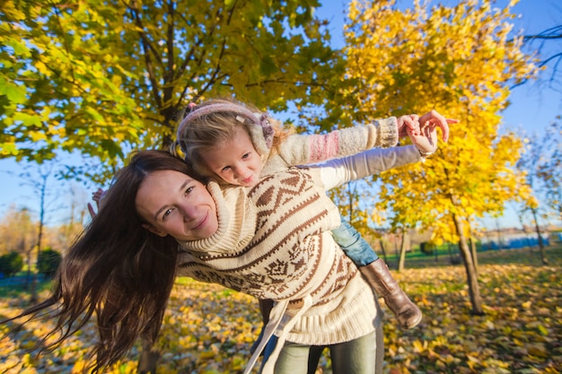 Portrait de jolie fille et heureuse mère s'amuser dans la forêt d'automne jaune par une chaude journée ensoleillée Photo Premium