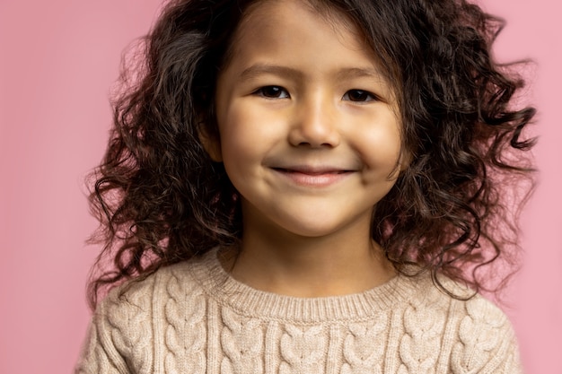 Portrait De Petite Fille Enfant 5 Ans Aux Cheveux Boucles Fonces Peau Brune Charmant Sourire Yeux Marrons Portant Un Pull Beige Souriant A La Recherche Photo Premium