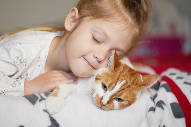 Portrait D Une Petite Fille Enfant Mignonne Qui Embrasse Un Chat Rousse Avec Tendresse Et Amour Et Sourit De Bonheur Photo Premium