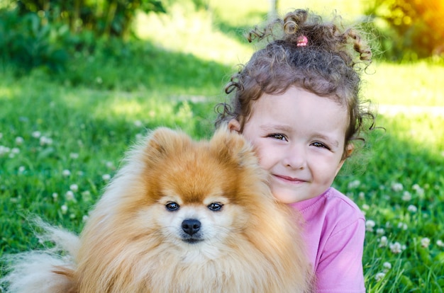 Portrait De Petite Fille Heureuse Etreignant Un Chien A L Exterieur Beau Bebe Et Spitz Pomeranien Enfant Et Animal De Compagnie Cherchent Photo Premium