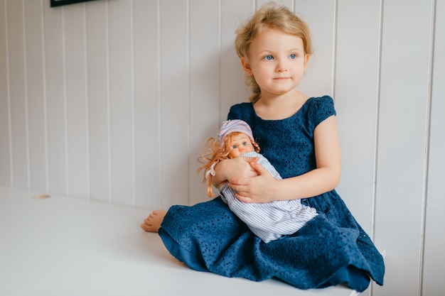 Portrait De Petite Fille Mignonne Tient Sa Belle Barbie Se Trouve Dans La Chambre De Bebe Lumineuse Regarde De Cote Photo Premium