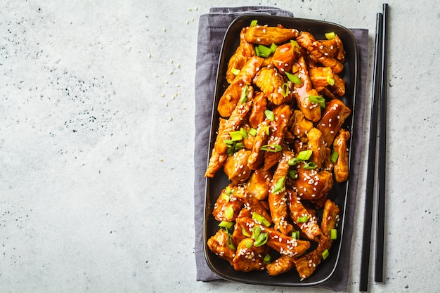 Poulet Teriyaki Au Sésame, Oignon Vert Dans Une Assiette Noire, Vue De Dessus. Photo Premium