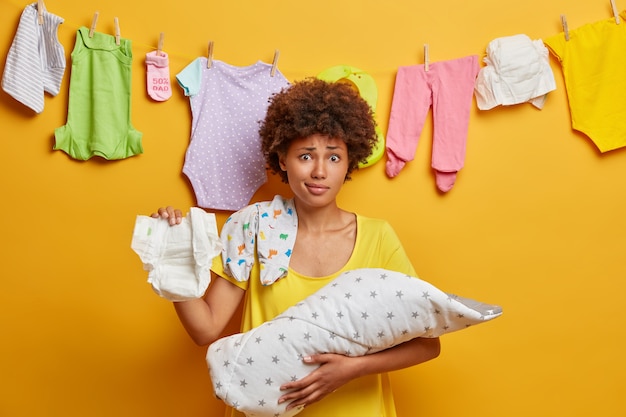 Prendre Soin Du Nouveau Ne La Mere Aux Cheveux Boucles Perplexe Tient La Couche Le Bebe