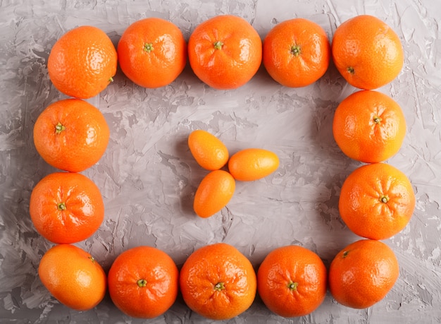 Rangées de mandarines formant un rectangle et trois kumquats à l'intérieur, vue de dessus. Photo Premium