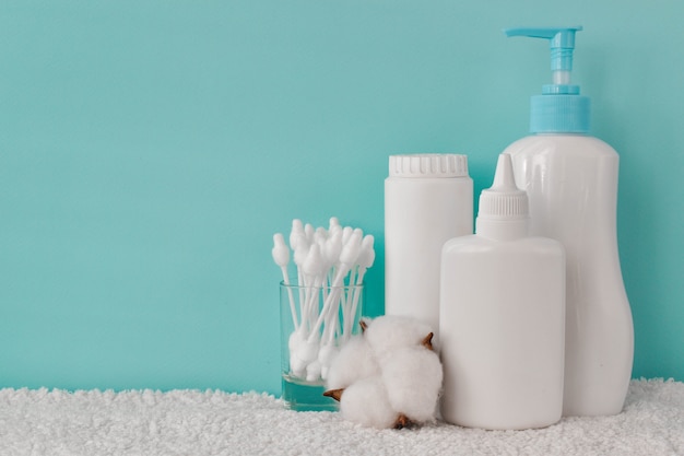 Un Recipient Avec De La Poudre Pour Bebe Une Bouteille De Talc Du Savon Liquide Et Des Cotons Tiges Sur Une Etagere Photo Premium