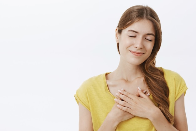 Reveuse Jeune Fille Heureuse Avec Un Beau Sourire Se Sentir Nostalgique Fermer Les Yeux Et Se Tenir La Main Sur Le Coeur Photo Gratuite