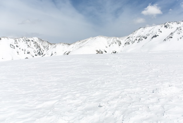 Rochers sur la neige couverte de montagne sous le ciel bleu Photo Premium