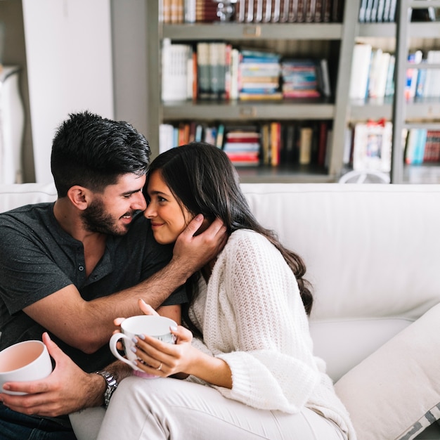 Romantique Jeune Couple Assis Sur Un Canapé Tenant Une Tasse De Café Photo Gratuite 