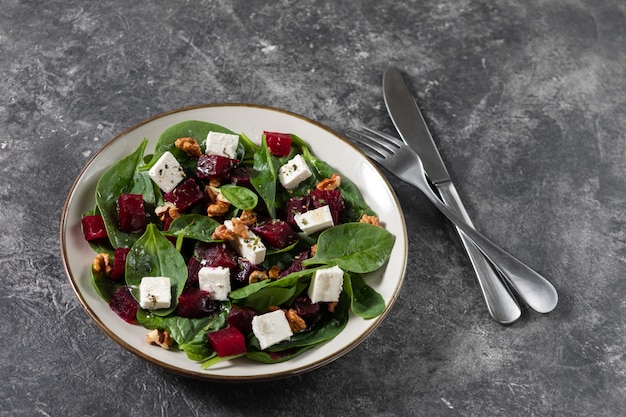 Salade de betteraves frites, d'épinards, de roquette, de fromage de chèvre doux et de noix dans une assiette légère. vue de dessus, espace de copie. Photo Premium