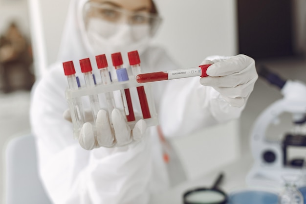 Un scientifique dans un équipement spécial montre un échantillon de test de coronavirus Photo gratuit