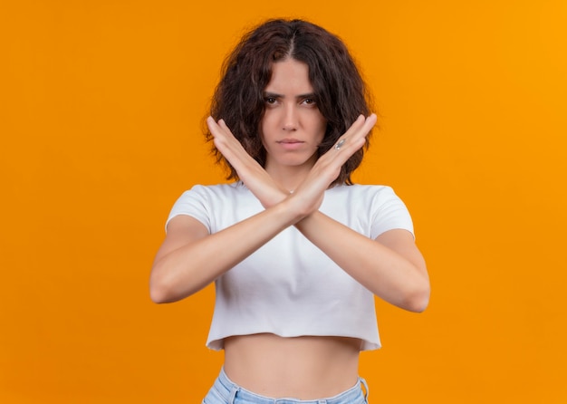 Sérieusement à la belle jeune femme gesticulant arrêt sur mur orange isolé avec espace copie Photo gratuit