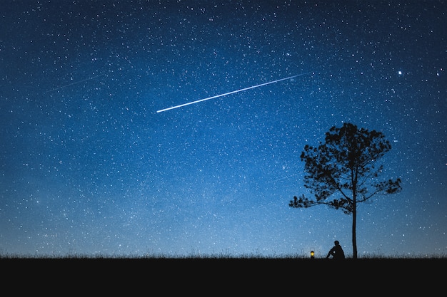Silhouette, homme, séance, montagne, ciel, nuit, à, étoile filante seul concept. Photo Premium