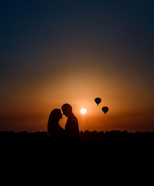 silhouettes-couple-se-serrant-autres-devant-coucher-soleil-ballons-aeriens-dans-ciel_8353-4003.jpg
