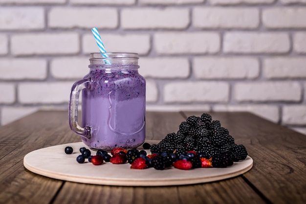 Smoothie frais au yaourt fait maison de baies sauvages dans un bocal en verre sur un vieux millésime, gros plan, mise au point sélectionnée. récolte . Photo Premium