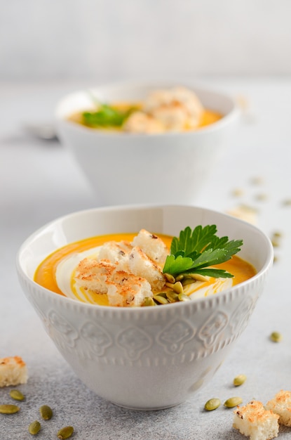 Soupe de potiron à la crème, croûtons, graines de citrouille et persil sur un fond gris en béton ou en pierre. Photo Premium