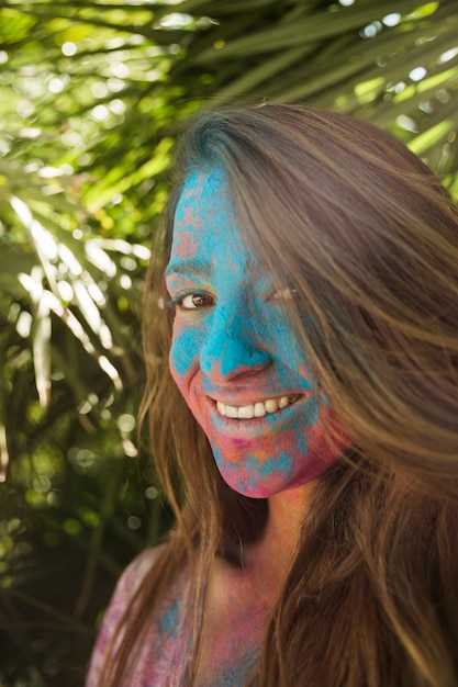 Souriant Visage De Jeune Femme Couverte De Couleur Holi Regardant La Caméra Photo Gratuite