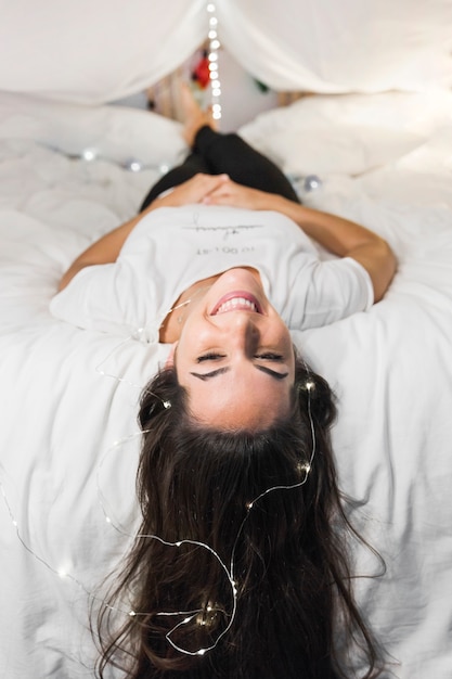 Souriante Jeune Femme Allongée Sur Le Lit Avec Un Ferry Sur Sa Tête Photo Gratuite 