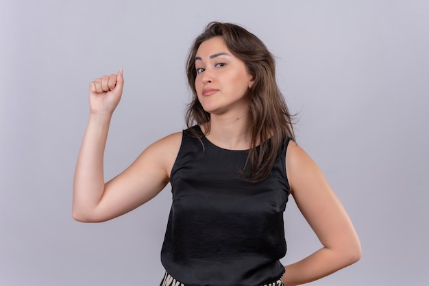 Souriante Jeune Femme Portant Un Maillot Noir Poing Leve Avec Une Main Et Un Autre Jeu De Mots Sur Le Dos Sur Le Mur Blanc Photo Gratuite