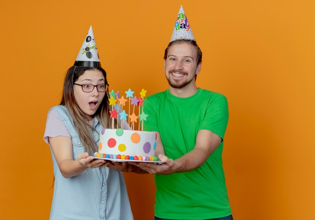 Sourire Bel Homme En Chapeau De Fete Tient Le Gateau D Anniversaire Et Surpris Jeune Fille Portant Chapeau De Fete Tient Et Regarde Le Gateau Isole Photo Gratuite