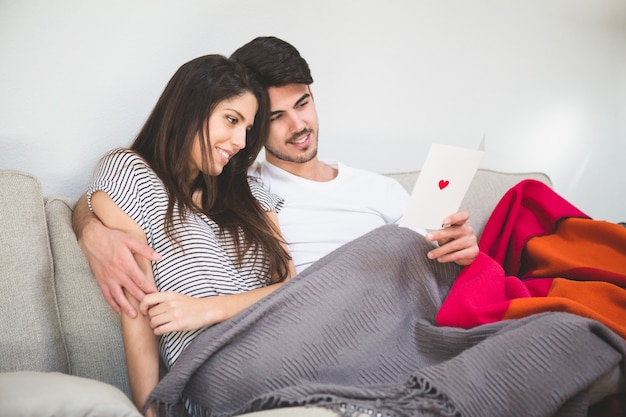 Sourire Couple Regardant Une Carte Postale Avec Un Coeur Photo Gratuite