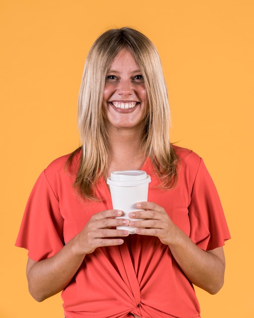 Sourire heureuse femme tenant une tasse de café jetable Photo gratuit