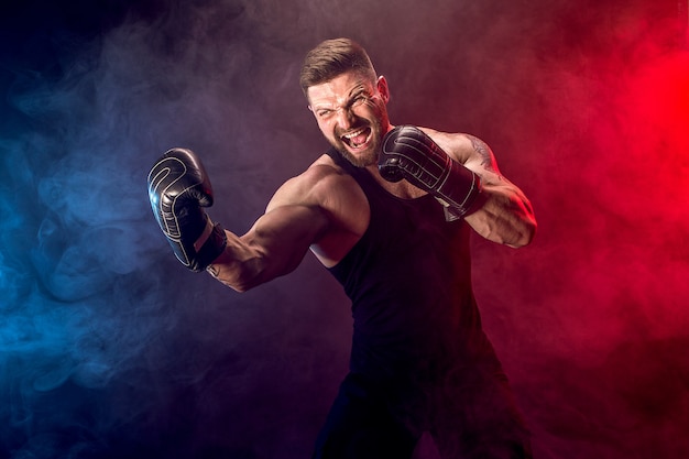 Sportif muay boxeur thai se battre sur un mur noir avec de la fumée. Photo Premium