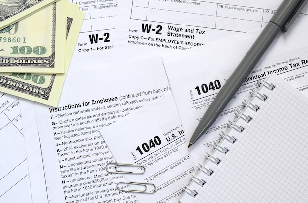 Le stylo, le cahier et les billets d'un dollar se trouvent sur le formulaire d'impôt 1040 us déclaration de revenus des particuliers Photo Premium