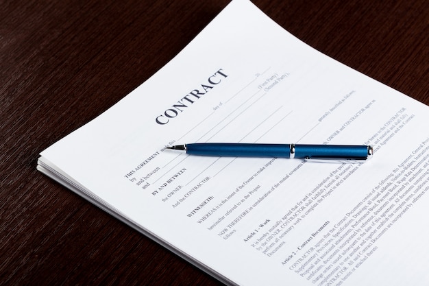 Stylo et papiers contractuels sur un bureau en bois Photo Premium