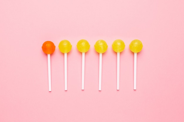 Sucette sucrée jaune et orange sur rose pastel. composition minimaliste. Photo Premium