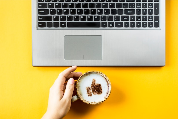 Une tasse de cappuccino sur laquelle est dessiné un sourire comme un pouce levé Photo Premium