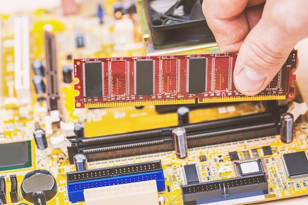 Technicien en informatique installant la mémoire ram de l'ordinateur dans la fente de la carte mère Photo Premium