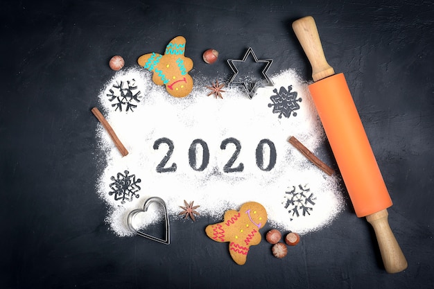 Texte 2020 fait avec de la farine avec des décorations sur fond noir. lay plat. Photo Premium