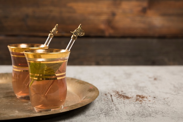 Thé arabe dans des verres à la menthe verte sur un plateau Photo gratuit