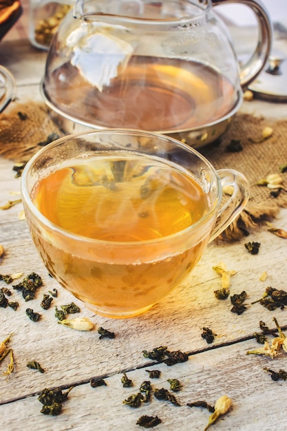 Thé vert au jasmin et noir avec citron transparent dans une petite tasse sur un fond clair. la théière mise au point sélective. Photo Premium