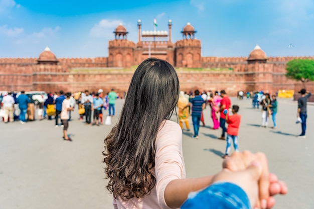 Tourisme asiatique jeune femme menant l'homme dans le fort rouge (lal qila) delhi avec drapeau indien dans le vieux delhi, inde Photo Premium