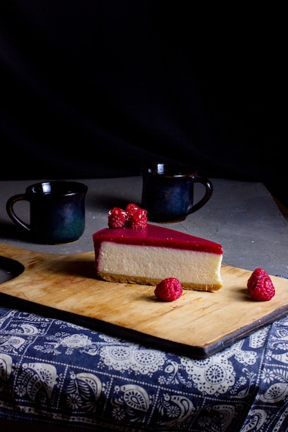 Une Tranche De Gateau Au Fromage Aux Framboises Place Sur Une Planche A Decouper En Bois Photo Gratuite