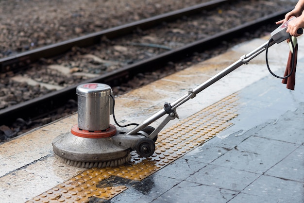 Travailleur utilisant une autolaveuse pour nettoyer et polir le sol. nettoyage du train de maintenance à la gare. Photo Premium