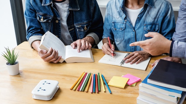 Tuteur d'école ou groupe d'étudiants collégiens assis à un bureau dans une bibliothèque étudiant et lisant, faisant ses devoirs et ses leçons se préparant à l'examen d'entrée, éducation, enseignement, concept d'apprentissage Photo Premium