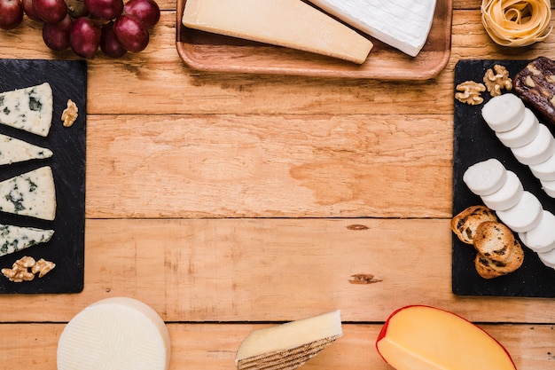 Types de fromage; les raisins; noix et pâtes disposées dans un cadre sur une surface en bois Photo gratuit