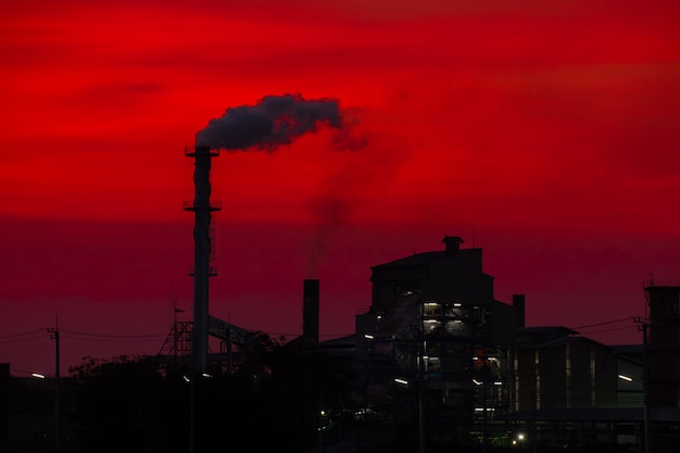 L'usine a libéré une cheminée de fumée au coucher du soleil Photo Premium