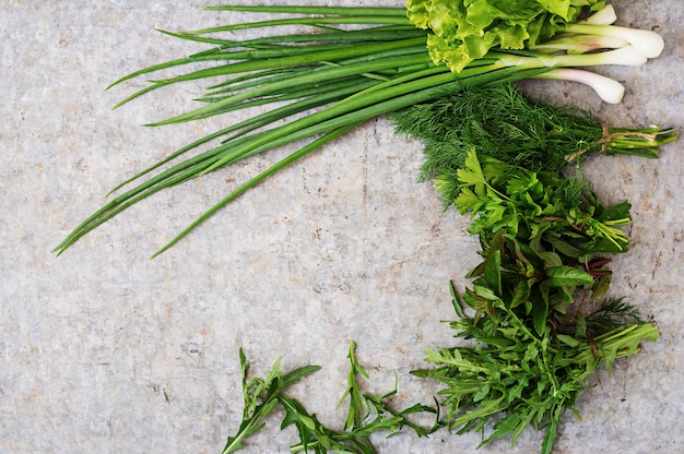 Variété D'herbes Biologiques Fraîches (laitue, Roquette, Aneth, Menthe, Laitue Rouge Et Oignon) Sur Fond Gris Dans Un Style Rustique. Vue De Dessus Photo gratuit